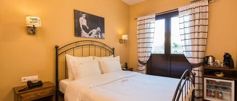 A hotel room with a bed, bedside table, lamp, air conditioning unit, and a small kitchenette.