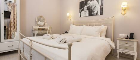A bedroom with a bed, bedside tables, a dresser, a mirror, and a wall-mounted picture.