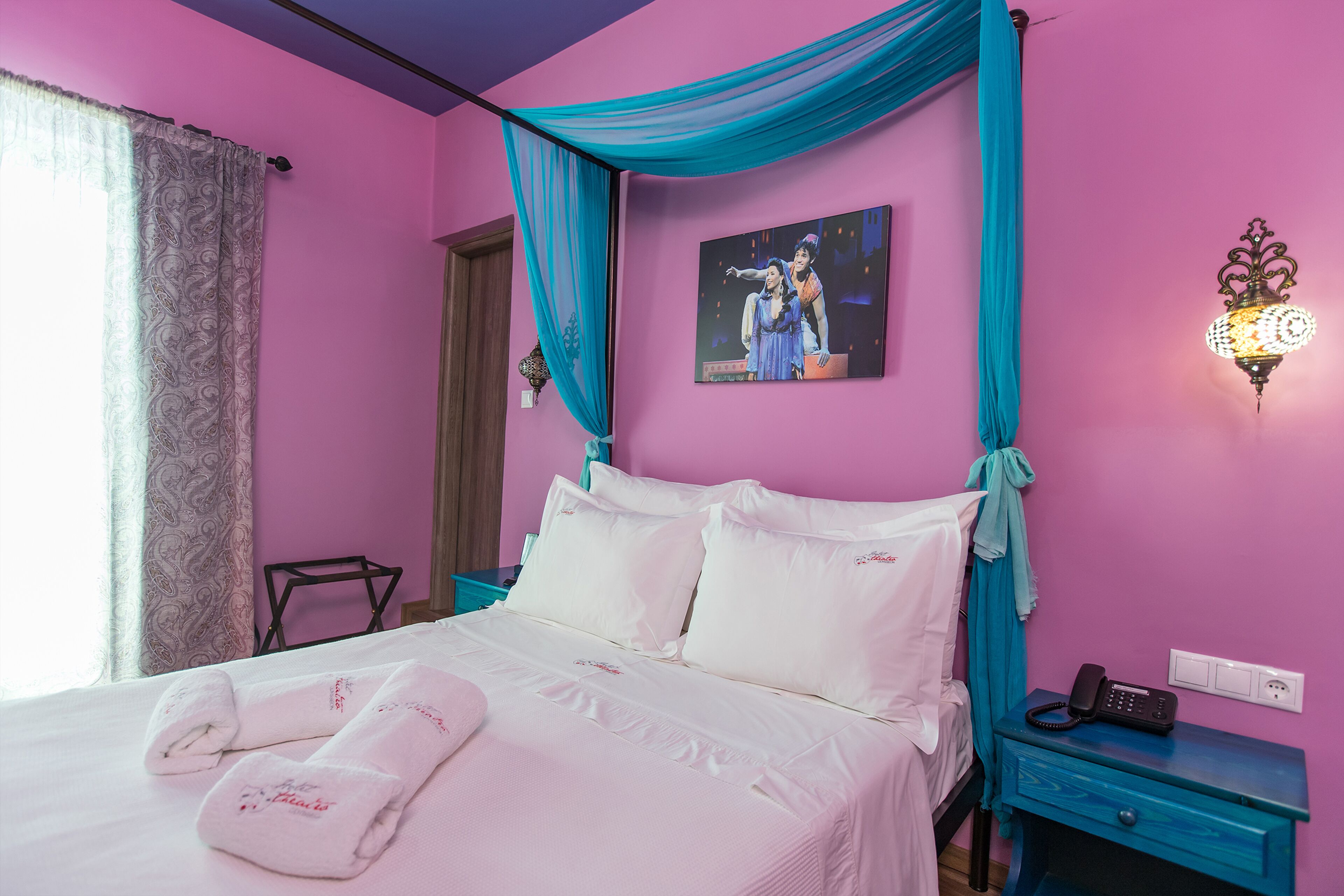 A bedroom with a bed, a nightstand, a wall-mounted lamp, and a poster on the wall.