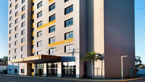 Un hotel de varios pisos con un diseño moderno, que destaca por una estructura vertical y un techo plano.