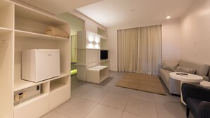 Una sala de estar moderna con un sofá, una mesa de centro, un televisor y estanterías empotradas.