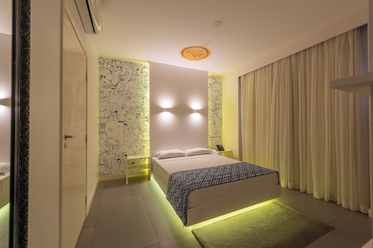 Un dormitorio moderno con una cama, mesitas de noche y una pared con un mural.