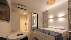 Una habitación de hotel moderna con cama, mesita de noche y espejo.