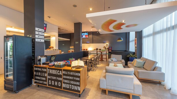 Un vestíbulo moderno de hotel con mostrador de recepción, zona de estar y un amplio ventanal que proporciona luz natural.