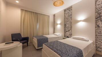 A hotel room with two beds, a desk, a chair, and a curtain.