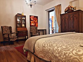 Una camera da letto con un letto grande, due sedie, un armadio in legno e un quadro appeso al muro.