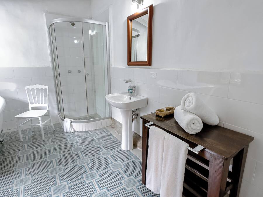 Un baño con ducha, lavamanos y tocador con toallas.