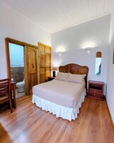 Una camera da letto con un letto in legno, un comodino, una sedia e un armadio in legno.