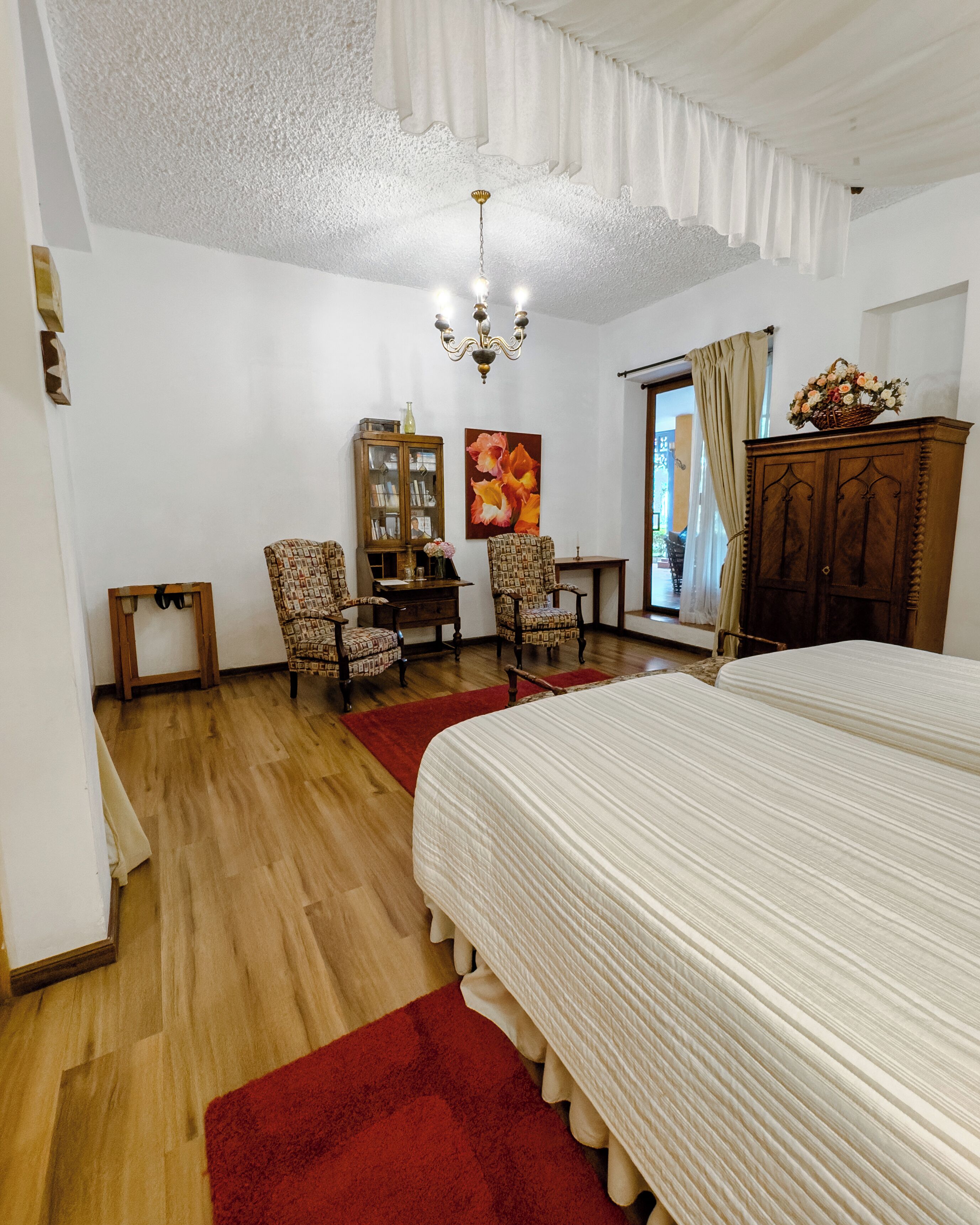 Un dormitorio con una cama grande, dos sillas, un armario y un cuadro en la pared.