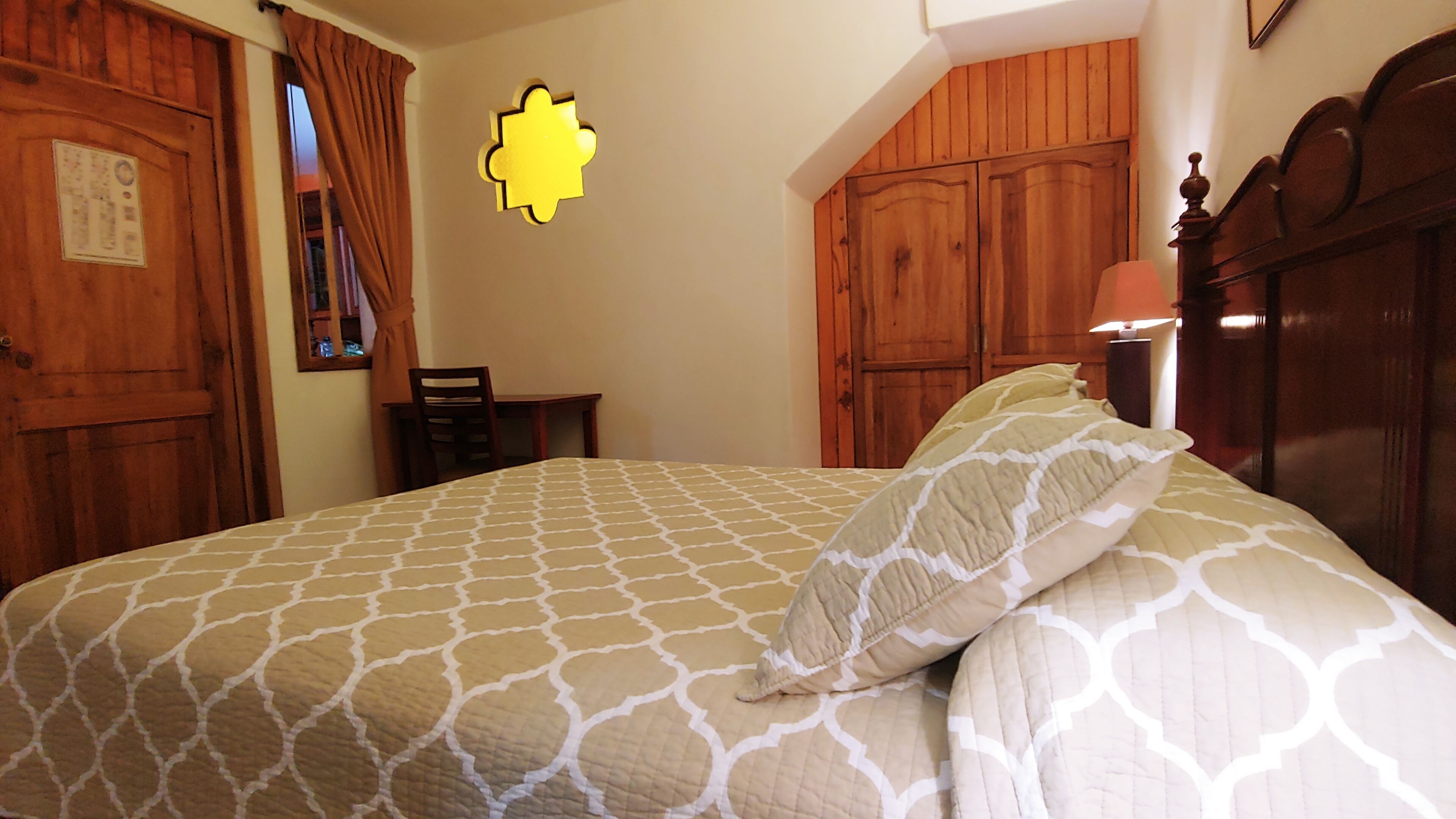 A bedroom with a bed, wooden wardrobe, and a desk.