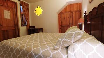 A bedroom with a bed, wooden wardrobe, and a desk.