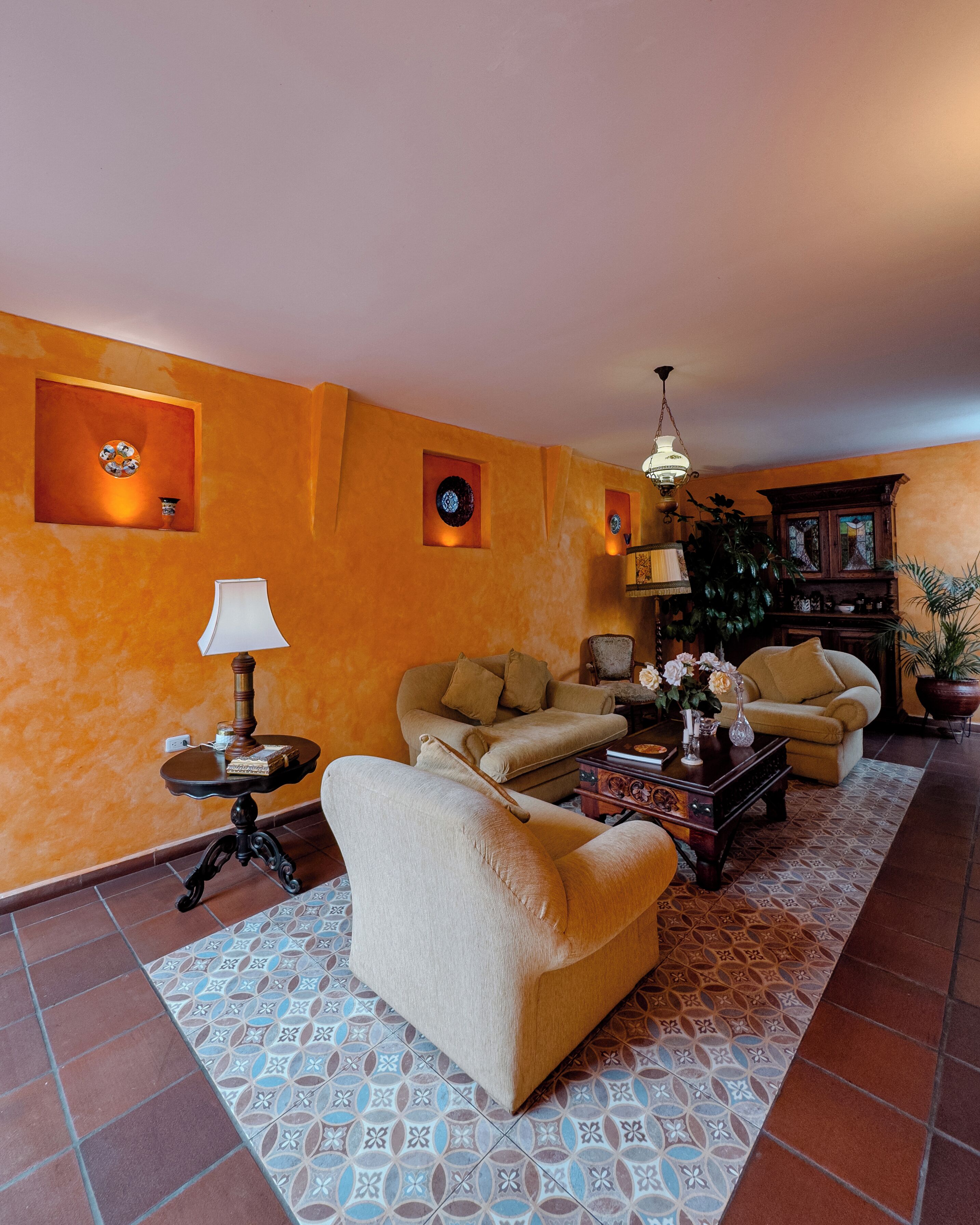 Un salon avec un canapé beige, un tapis à motifs et un meuble en bois.