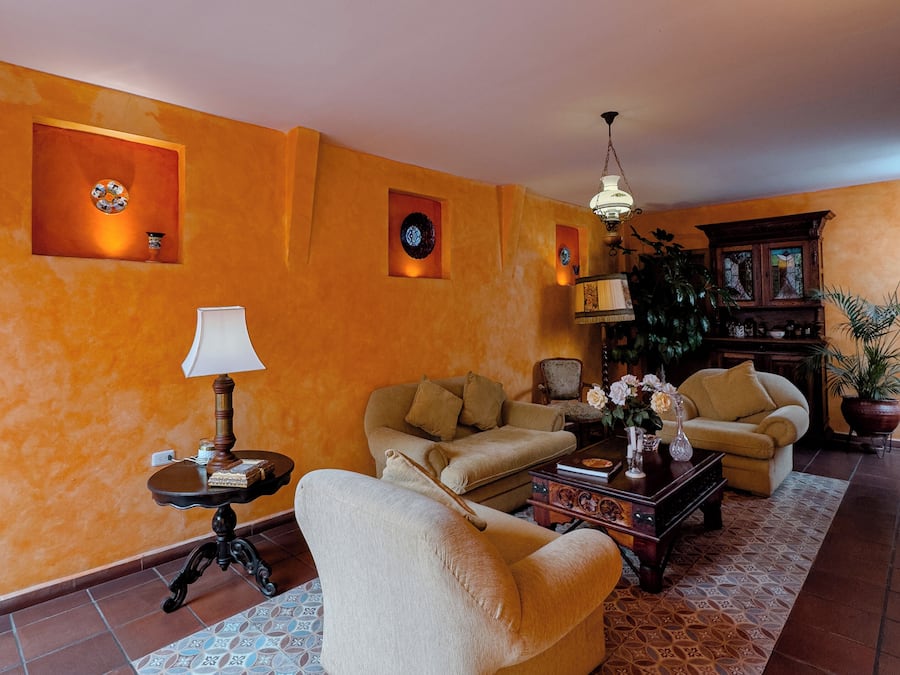 Un salon avec un canapé beige, un tapis à motifs et un meuble en bois.