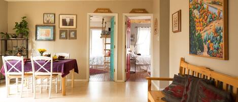 A living room with a wooden bench, a dining table with chairs, and a painting on the wall.