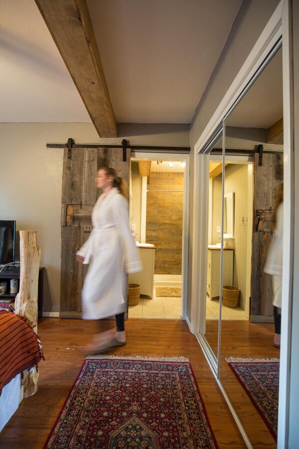 A modern interior with a wooden ceiling, a large mirror, and a sliding door leading to a bathroom.