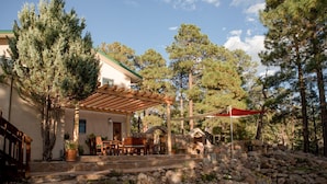 A covered patio with outdoor furniture, a stone fireplace, and a stone wall.