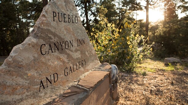 A stone sign with the text 'PUEBLO CANYON INN AND GALLERY'.