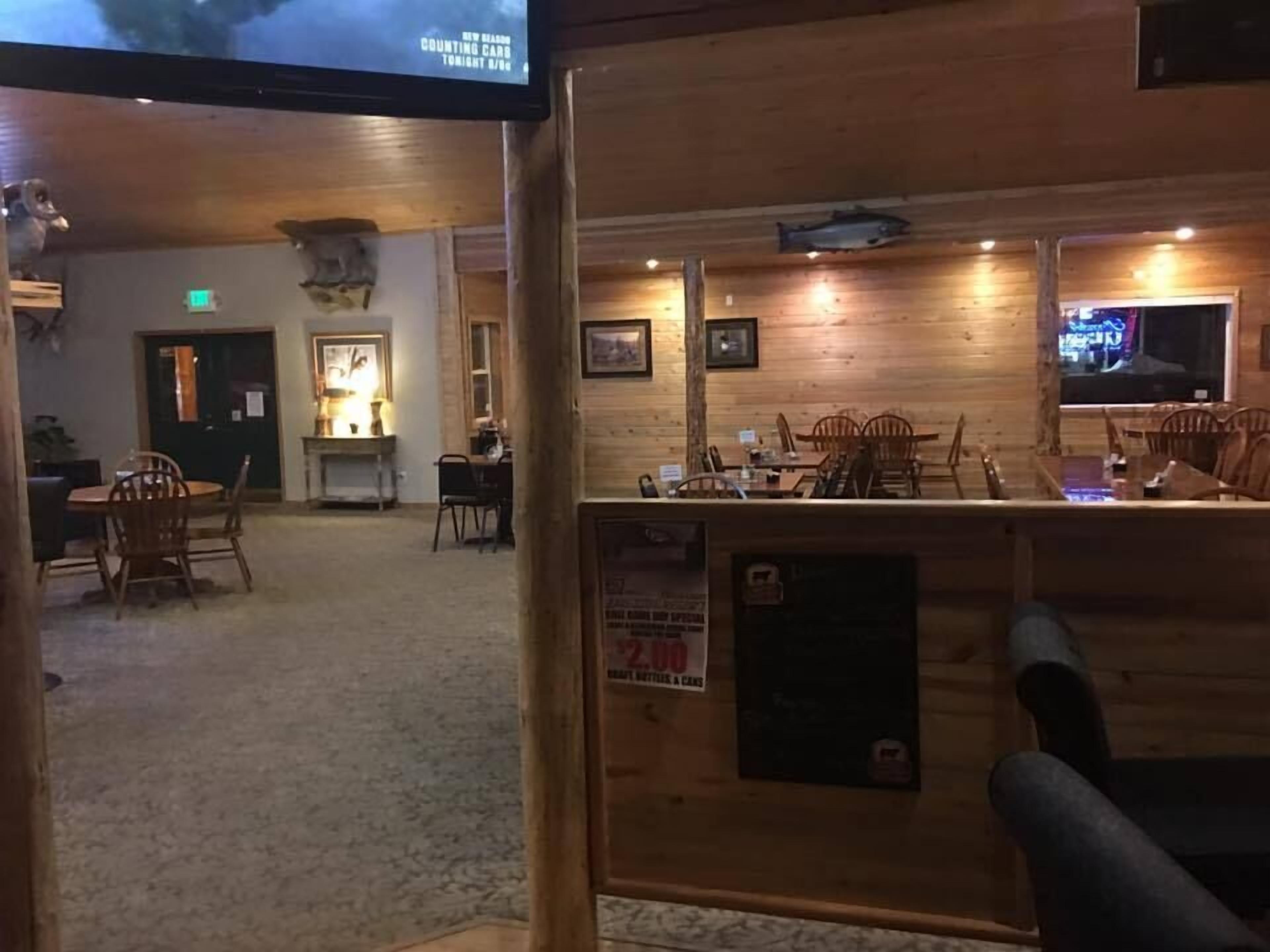 En restaurang med träinredning, träbord, trästolar och en tv-skärm.