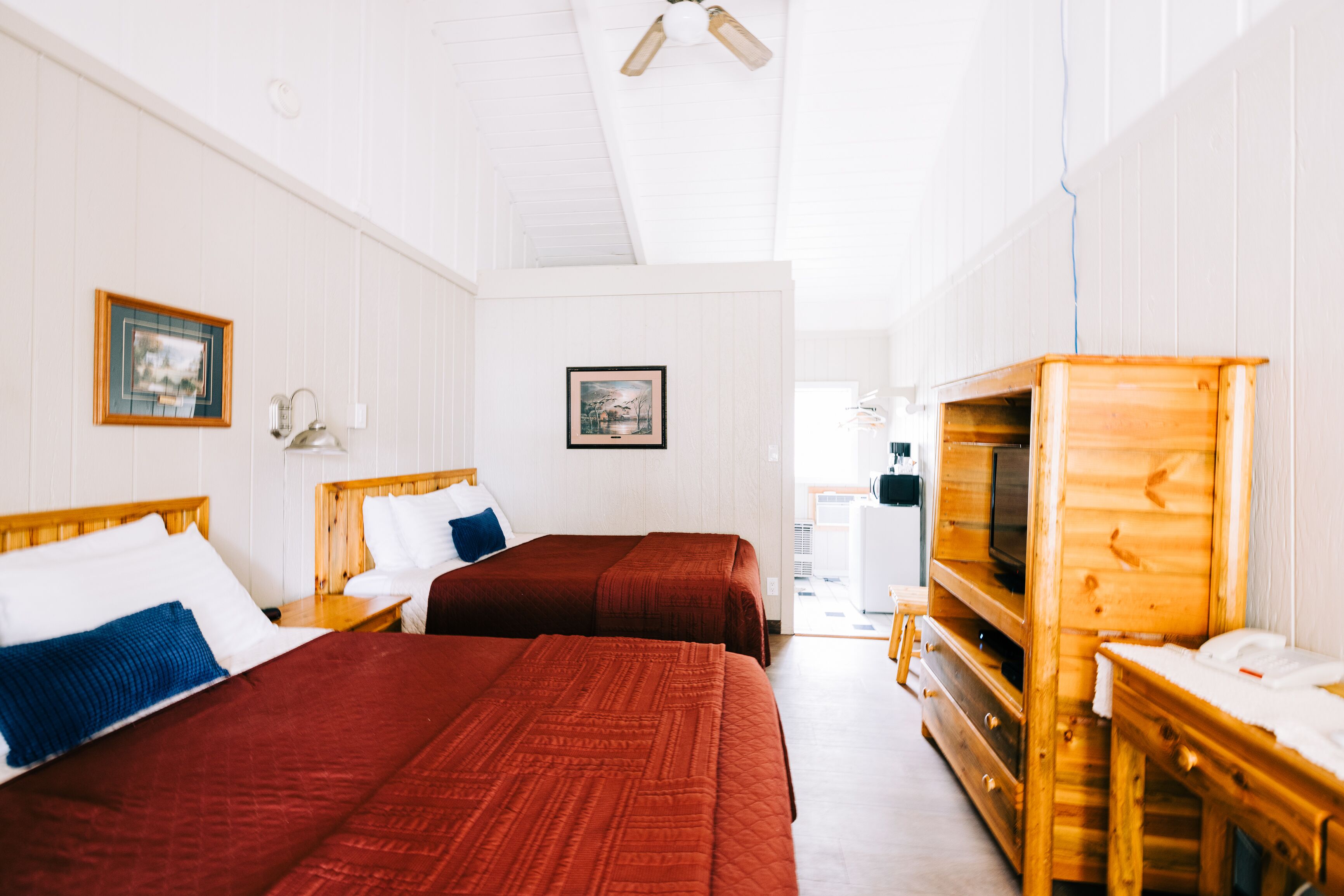 A hotel room with two beds, wooden furniture, and a television.