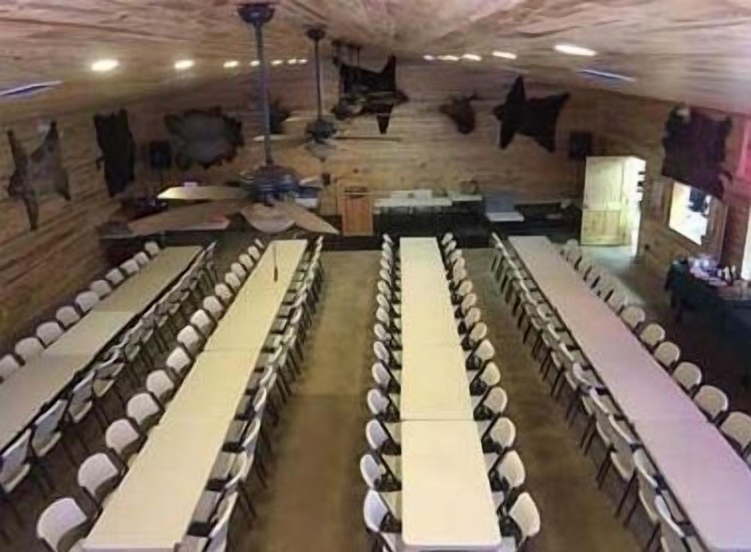 Une grande salle à manger avec de nombreuses tables et chaises, des murs en bois et des décorations au plafond.