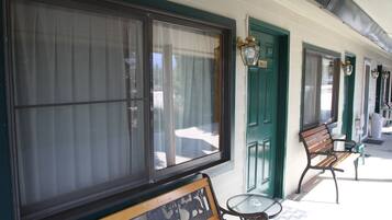 A row of green doors with a bench and a table outside a building.