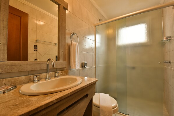 A bathroom with a marble sink, a glass shower enclosure, and a wooden vanity.