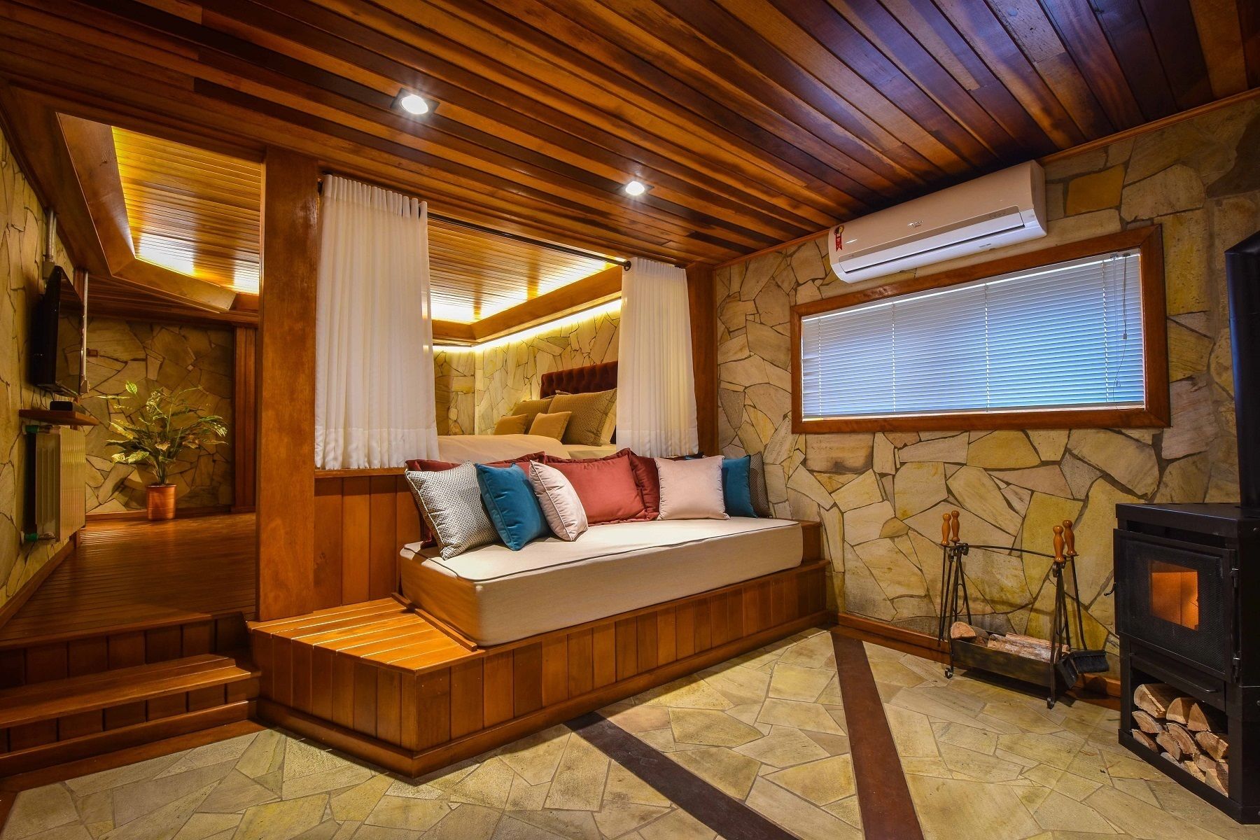 A cozy room with a wooden bench, stone walls, and a fireplace.