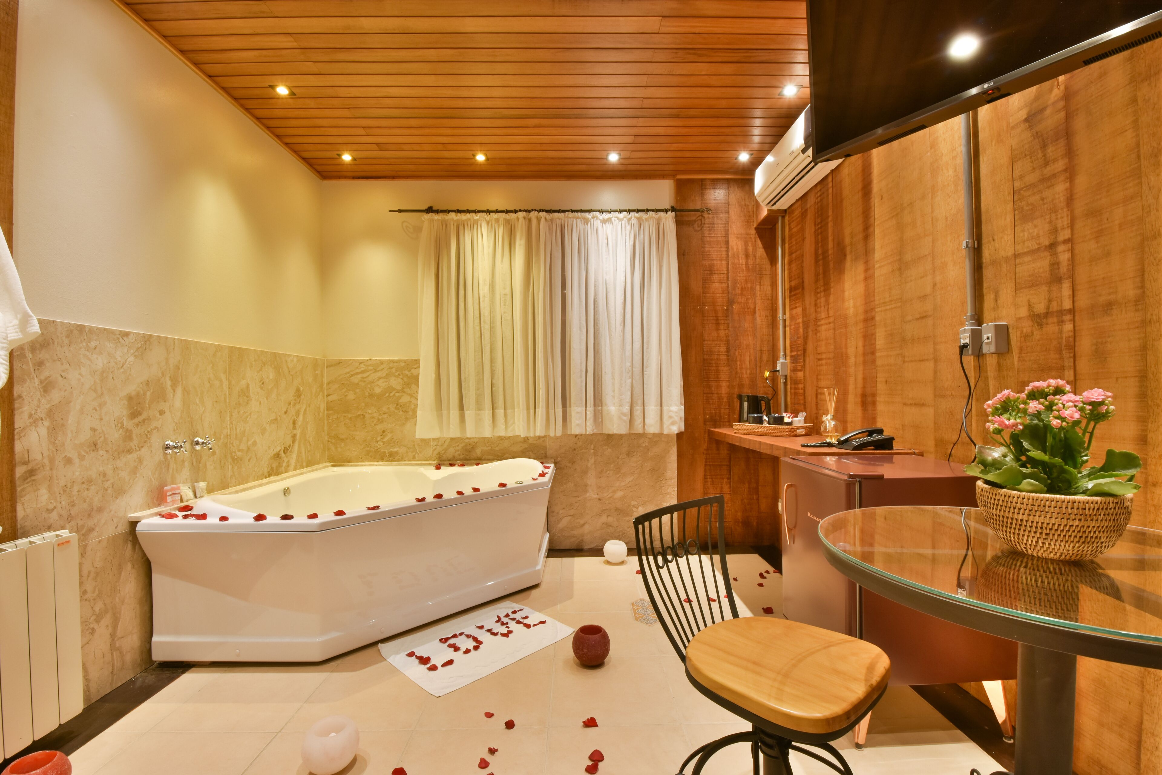 Un baño moderno con una bañera independiente, una mesita de vidrio y una silla.