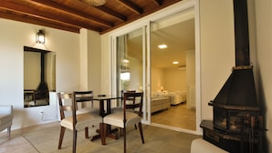 A cozy living room with a fireplace, a dining area with chairs and a table, and a sliding glass door leading to another room. - Pousada Borô (Gramado)