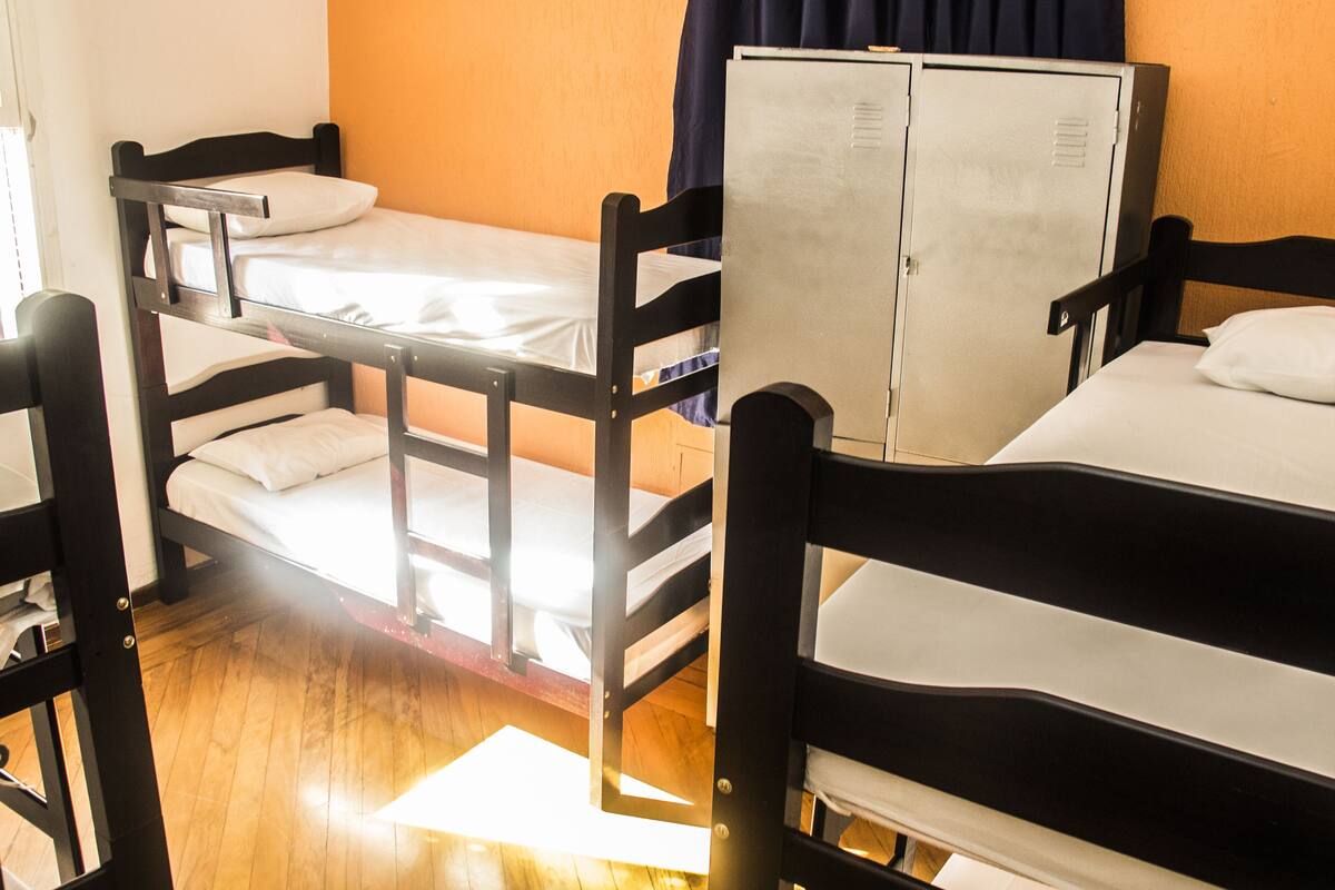 Ein Schlafraum mit Etagenbetten, einem Kleiderschrank und einem Fenster mit Vorhängen.
