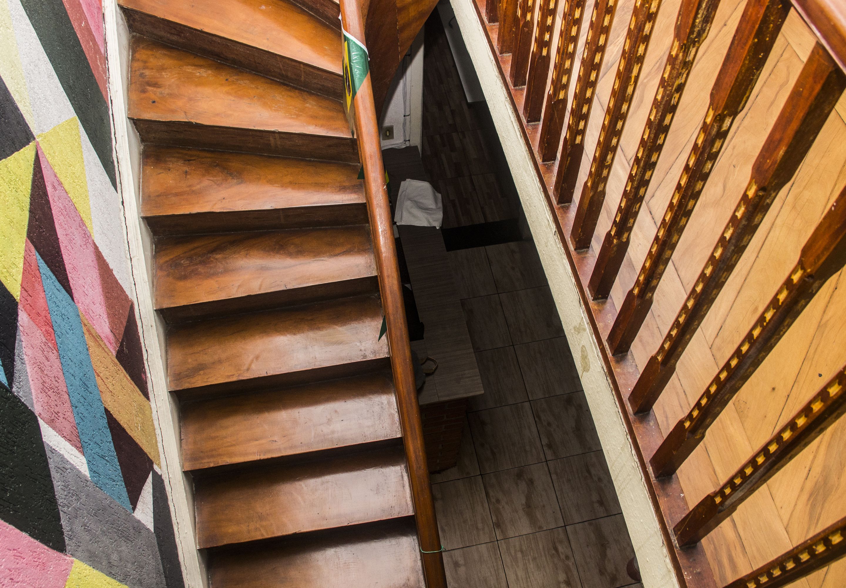 Una escalera de madera con una pared a la izquierda cuyo diseño presenta un patrón geométrico.