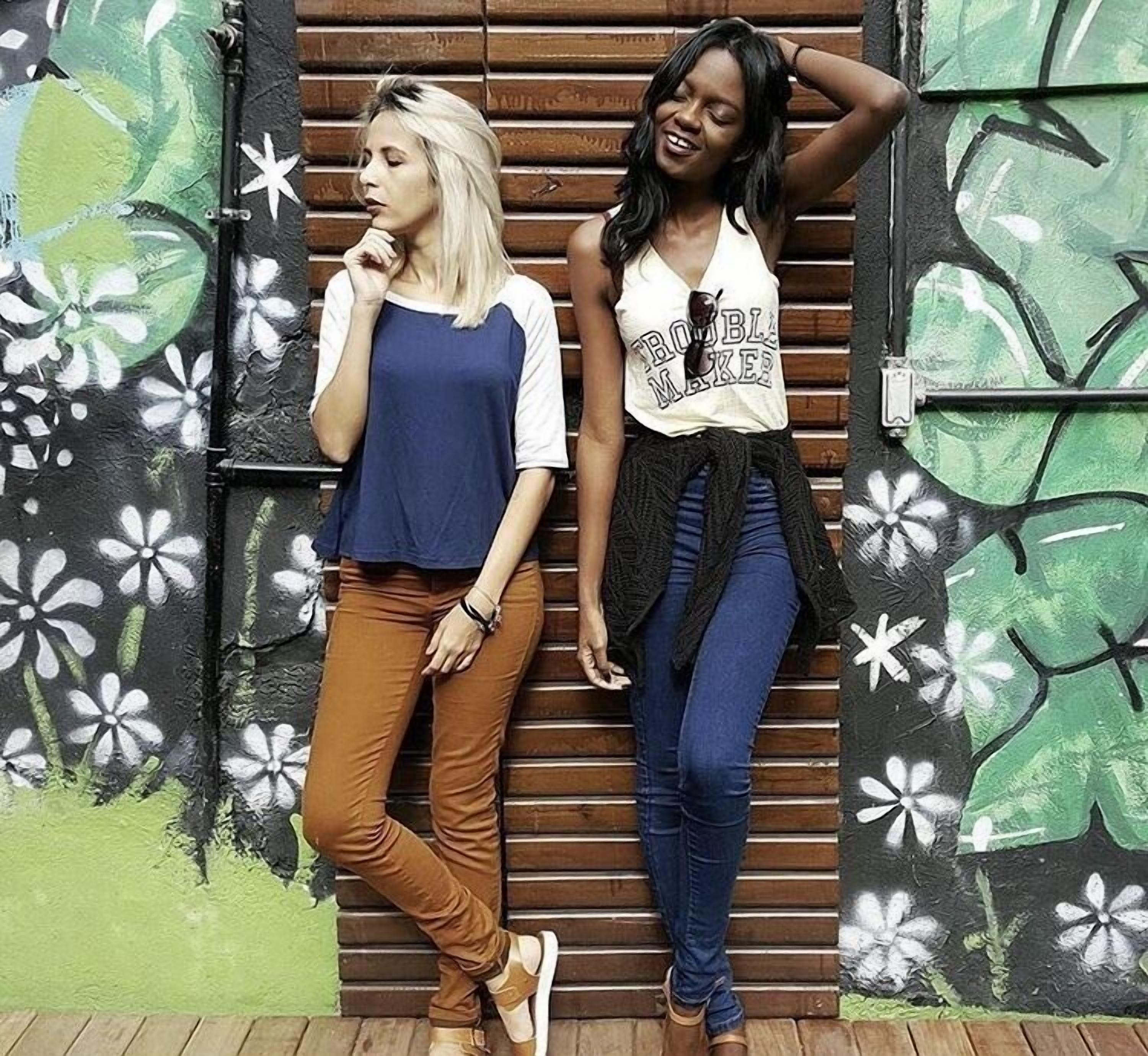 Dos personas de pie frente a una pared con diseño floral.