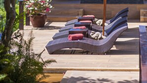 A covered outdoor seating area with lounge chairs, a table, and a potted plant. - Baan Ling Noi Villa (Koh Samui)
