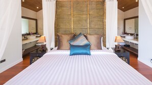 A large bed with striped bedding, two bedside tables with lamps, and a large mirror above the bed. - Baan Ling Noi Villa (Koh Samui)