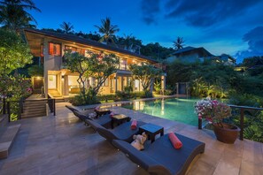Un resort moderno con piscina, sillas de descanso y un jardín bien cuidado.