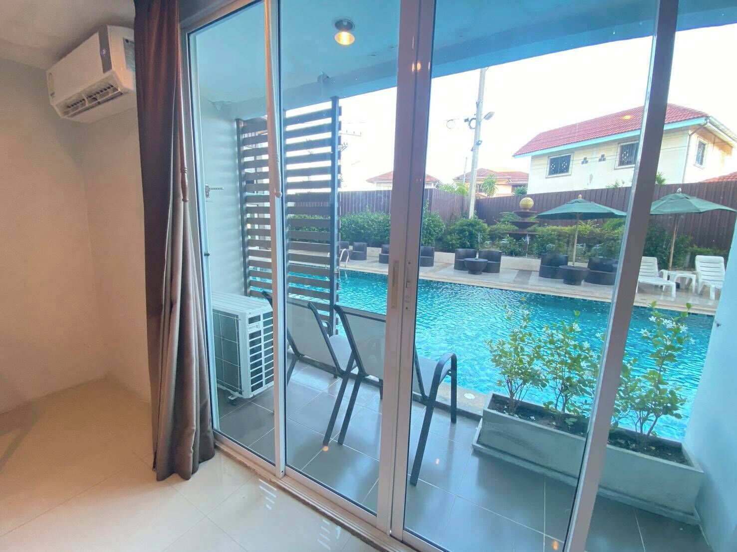 A room with a sliding glass door leading to a pool area, a ceiling fan, and a built-in air conditioning unit.