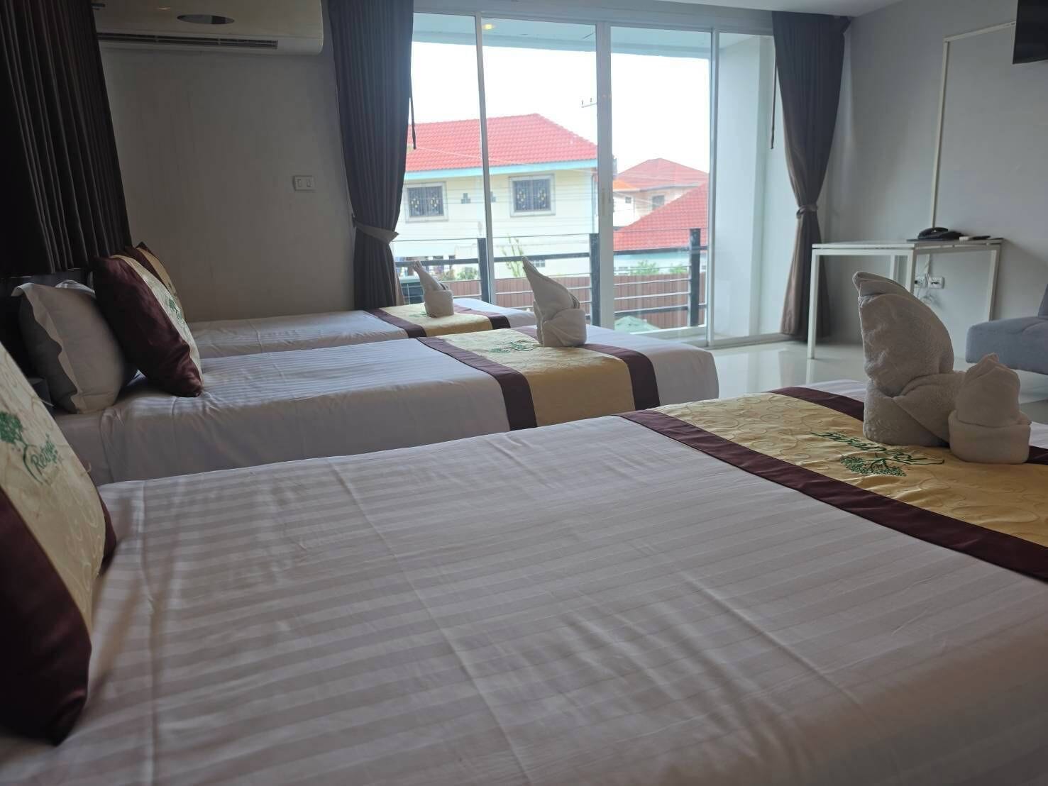 Een hotelkamer met twee bedden, een raam met uitzicht op gebouwen, en een bureau met een stoel.