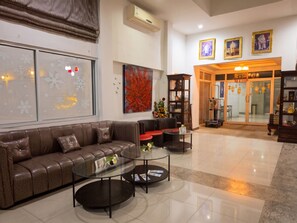 A modern living room with a brown leather sofa, glass coffee tables, and a red abstract painting. - Retreat Resort Pattaya (Pattaya)