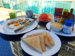 A breakfast table with plates of eggs, toast, and fruit, along with condiments and a glass of juice. - Retreat Resort Pattaya (Pattaya)