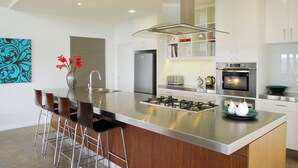 A modern kitchen with a central island, stainless steel appliances, and bar stools. - The Ridge - Gloucester (Gloucester)