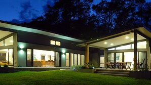 A modern two-story house with large glass windows and a well-lit outdoor area. - The Ridge - Gloucester (Gloucester)
