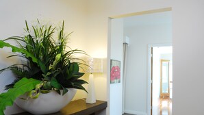 A hallway with a wooden floor, a white wall, and a white door at the end. - The Ridge - Gloucester (Gloucester)