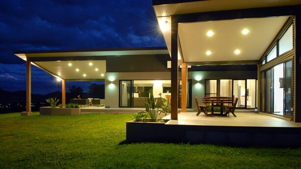 A modern house with a covered patio, outdoor seating, and a well-lit garden area. - The Ridge - Gloucester (Gloucester)