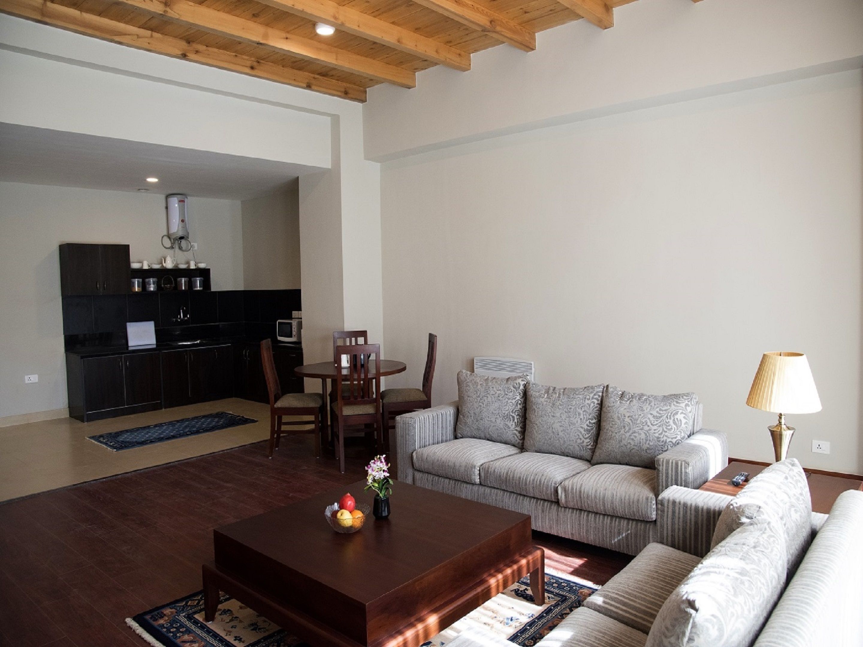 A modern living room with a sofa, coffee table, and a dining area with chairs and a table.