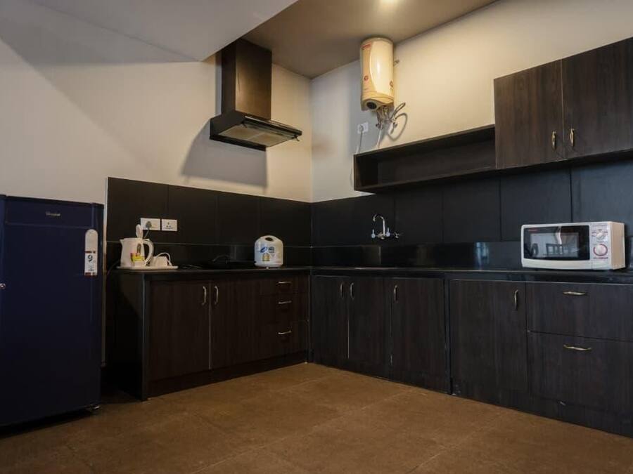 A compact kitchen with dark cabinetry, a built-in microwave, and a coffee machine.