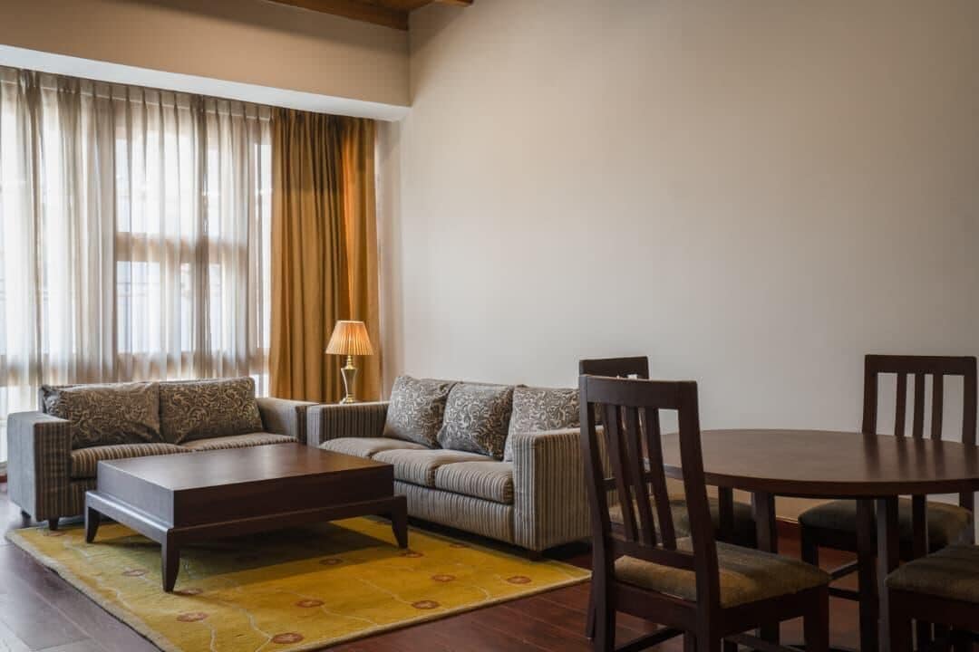 Uma sala de estar com um sofá, uma mesa de centro e uma mesa de jantar com cadeiras.