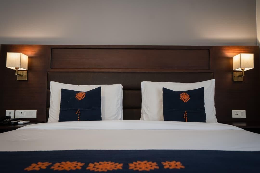 Een hotelkamer met een groot bed, twee wandlampen en een donker houten hoofdeinde.