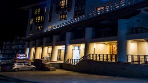 Un hotel de varios pisos con un estilo arquitectónico tradicional, que cuenta con un balcón con barandillas y ventanas iluminadas.