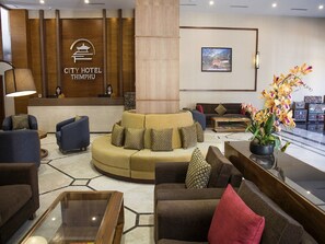 A hotel lobby with a reception desk, sofas, a coffee table, and a large potted plant. - City Hotel Thimphu (Thimphu)
