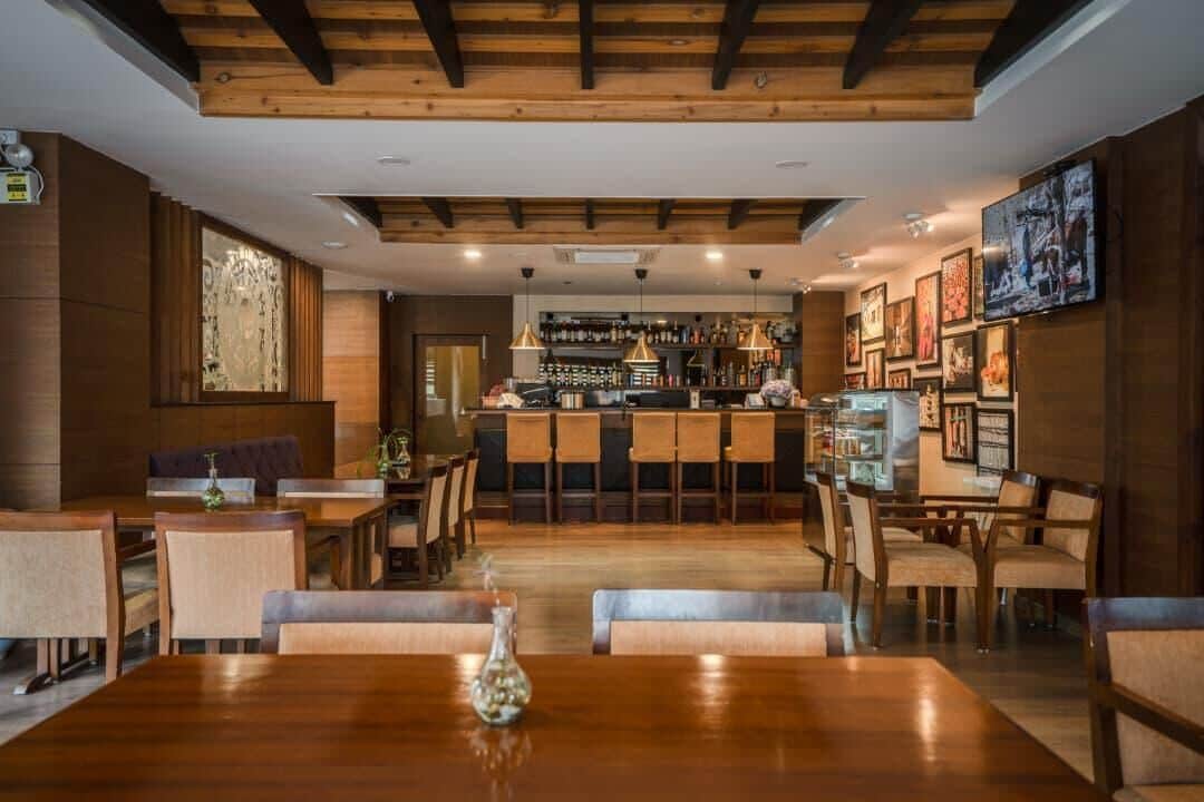 Un restaurante con área de bar, mobiliario de madera y cuadros en las paredes.
